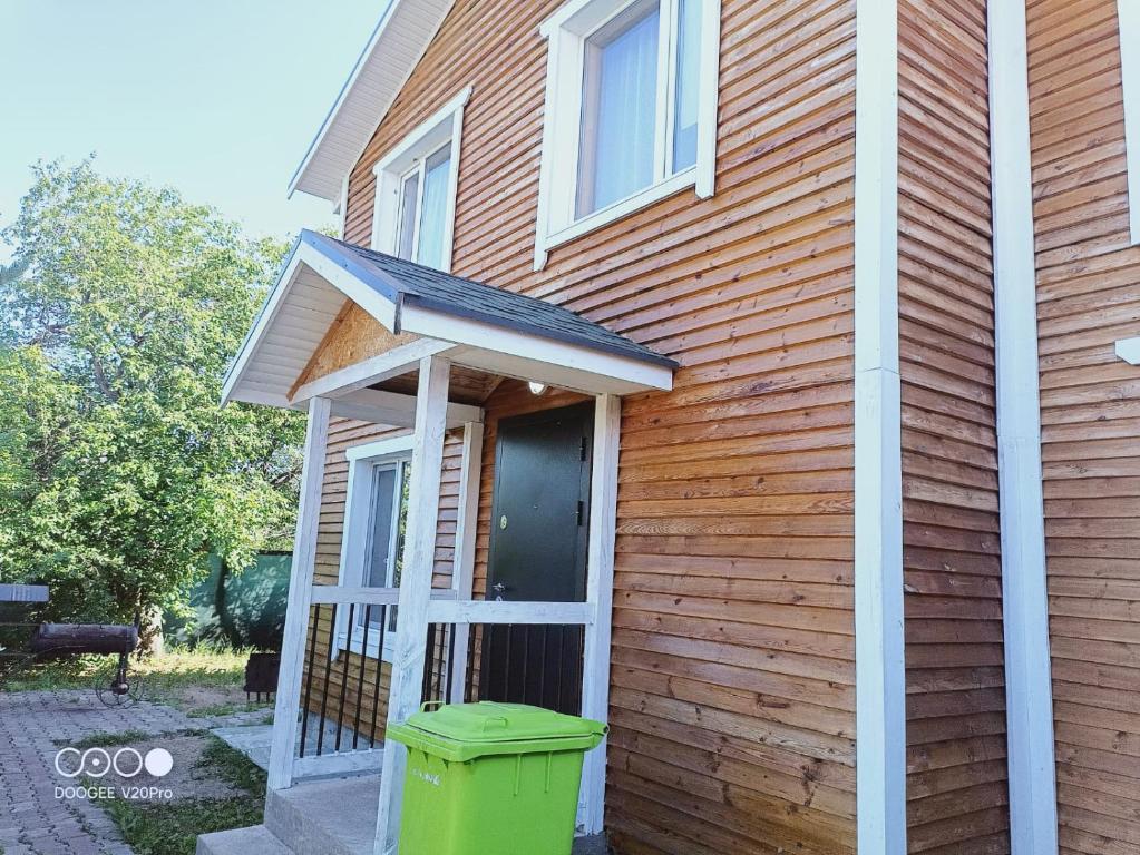 a house with a green trash can in front of it at Коттедж Бурабай улица Алатау 38 in Borovoye