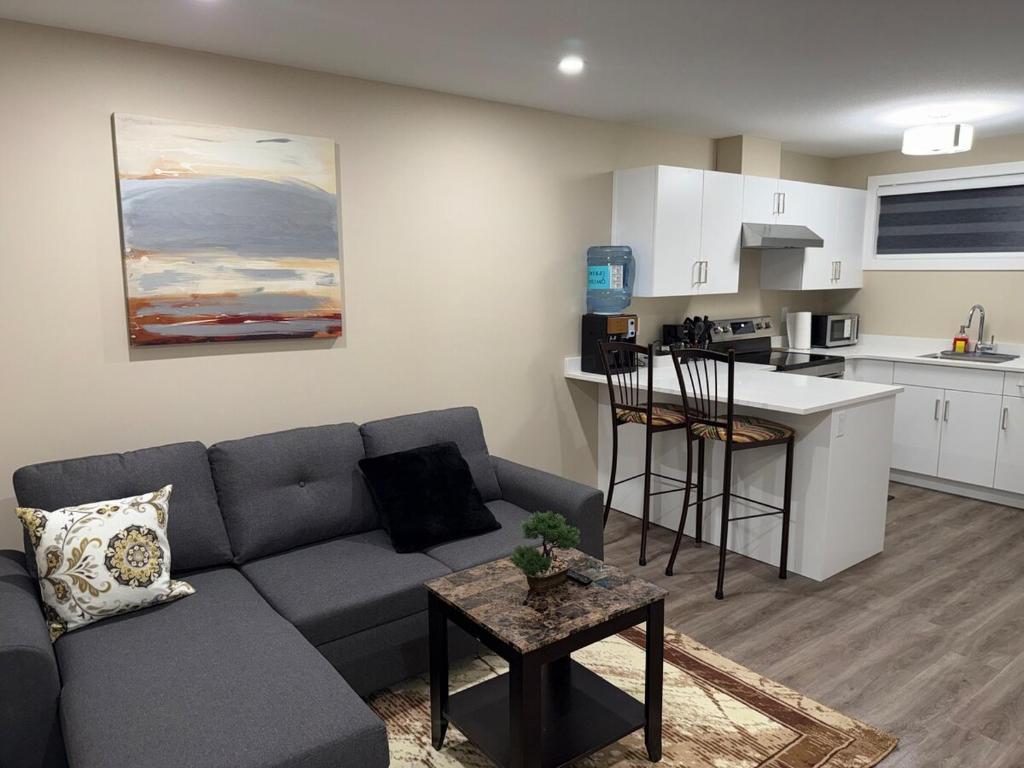 a living room with a couch and a kitchen at Modern Private Suite, Cozy, Stylish & Spacious in Regina