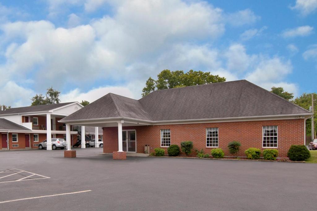 un grand bâtiment en briques rouges avec un parking dans l'établissement Super Inn Downtown, à Bardstown