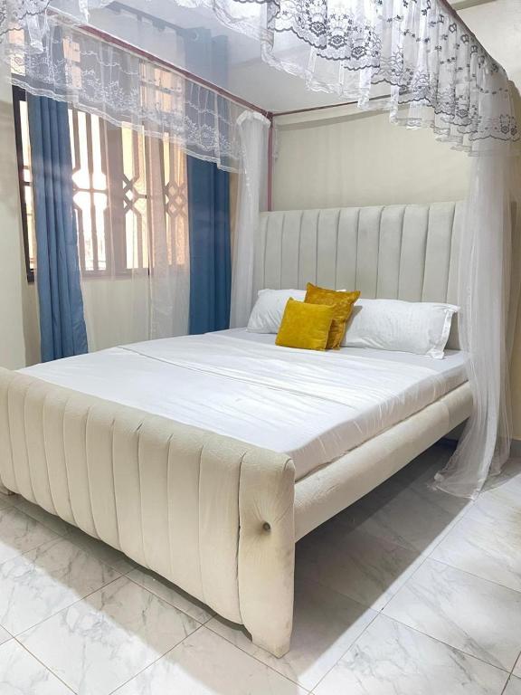 a large white bed with yellow pillows in a bedroom at M's BNB in Bungoma