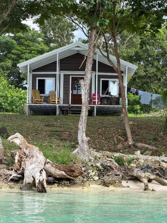 a small house on the shore of a body of water at Aore Shores Beachfront Bungalow in Aore Island