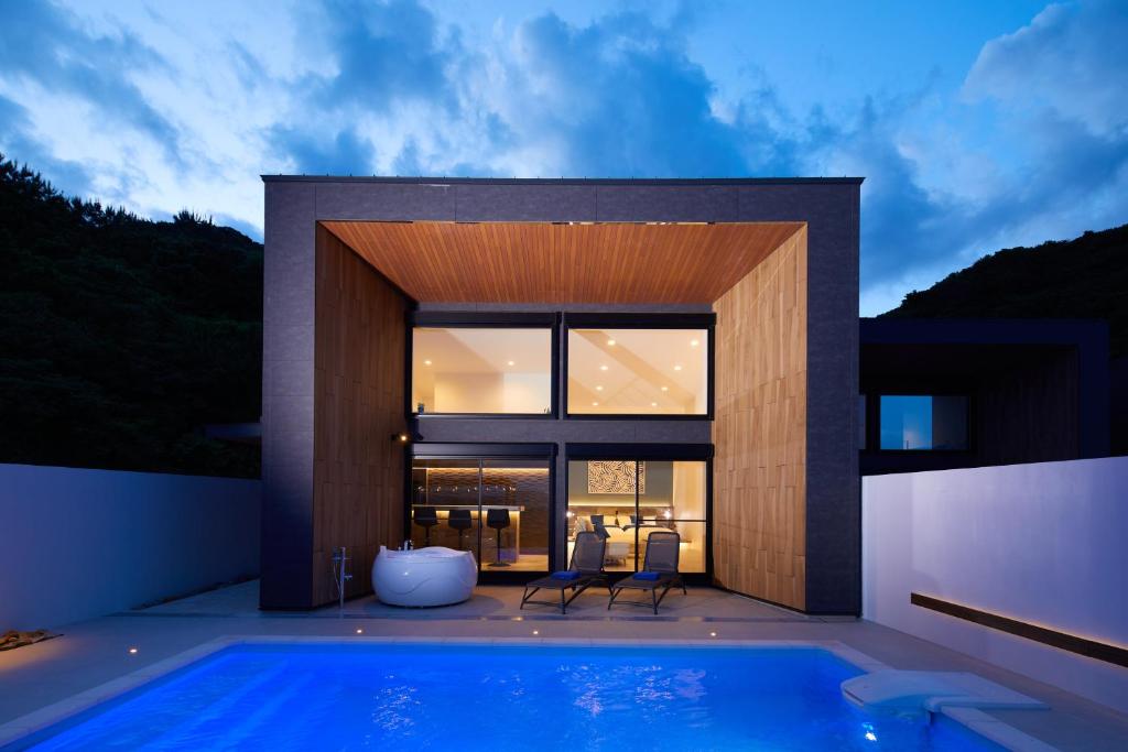 a house with a swimming pool and two chairs at Mare Blu Amami in Tatsugo