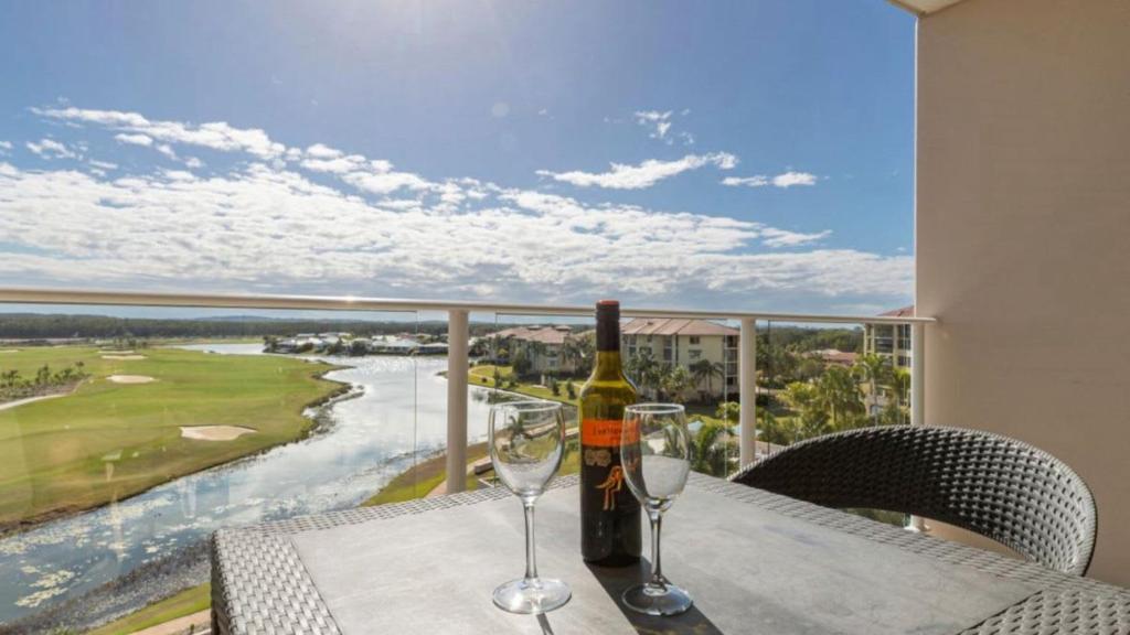 a bottle of wine and two glasses on a table at Lovely Studio Apartment Overlooking Golf Course! in Pelican Waters