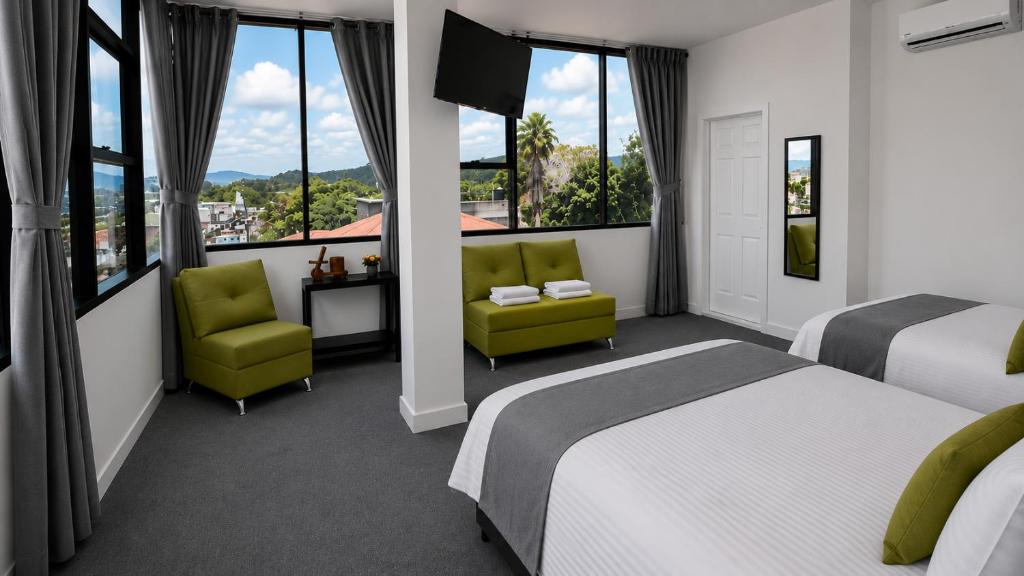 a hotel room with two beds and chairs and windows at hotel barmel in Siguatepeque