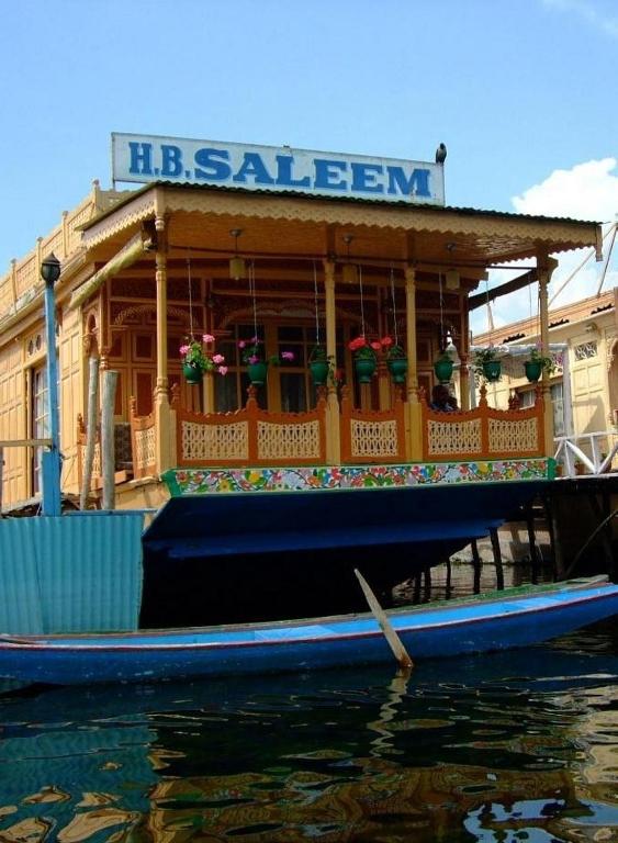 a boat sitting on the water in front of a building at Houseboat Saleem in Dal Lake