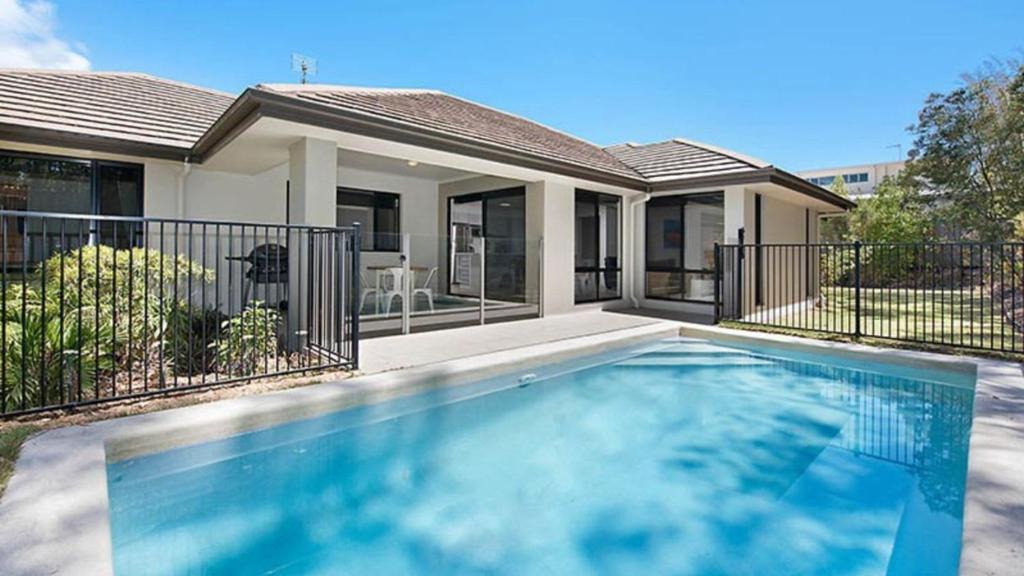 a swimming pool in front of a house at Hideaway -4BR Family Home with Pool, Near Beach in Caloundra