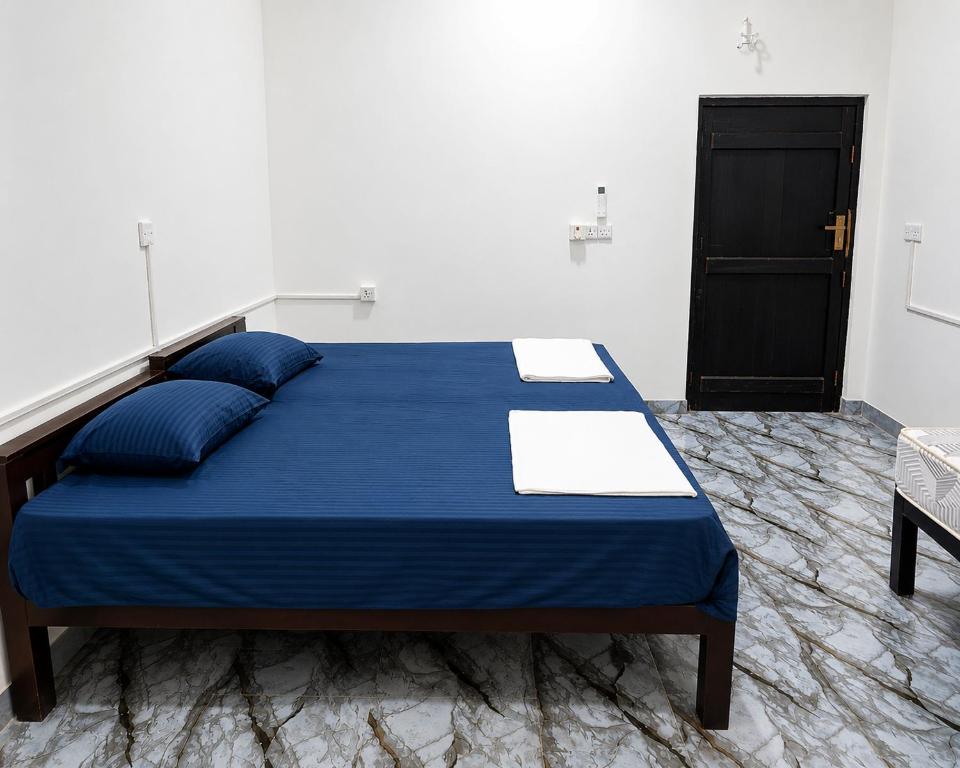 a bedroom with a blue bed and a black door at A to Z surf camp in Arugam Bay