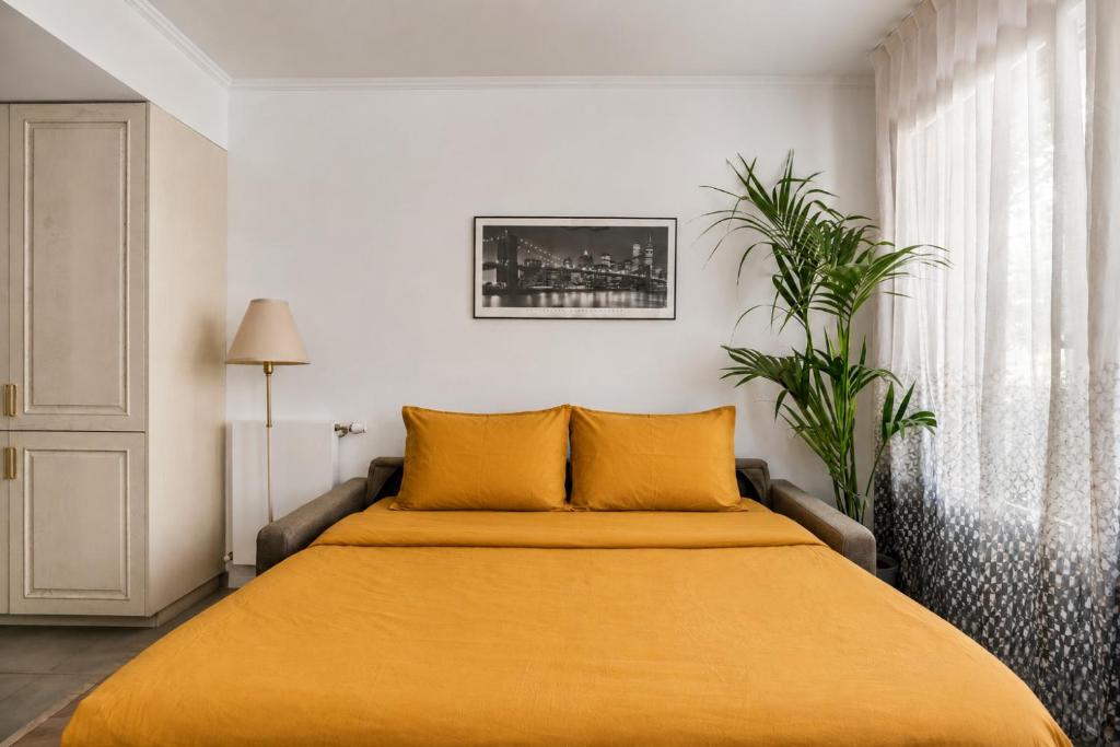 a bedroom with a bed with yellow sheets and a plant at Bright & Spacious Apartment near Paris 6 Guests in Clichy