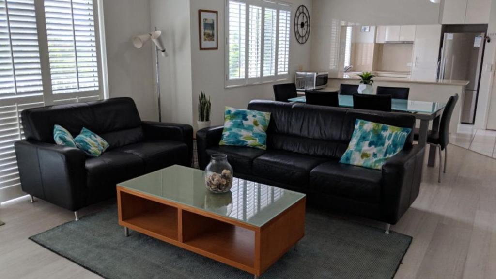 a living room with a black couch and a table at Spinnaker Seas Unit 2 in Caloundra