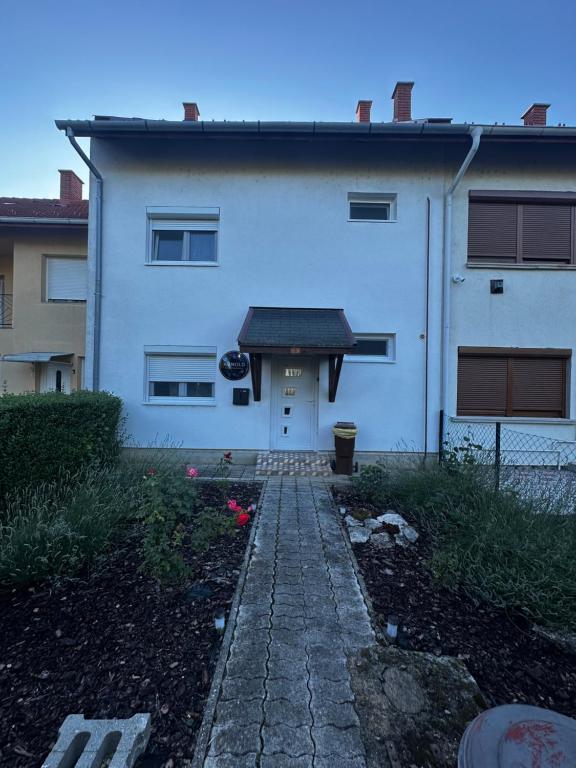 a white house with a black roof and a walkway at Arnold Apartmanház in Bük
