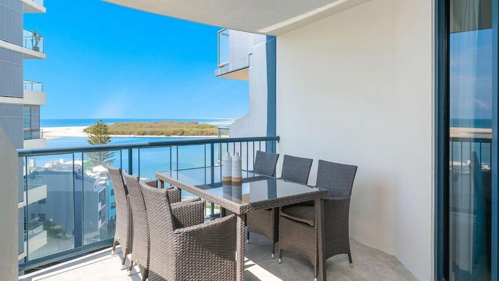 a dining room with a table and chairs on a balcony at Grand Pacific Unit 104 in Caloundra