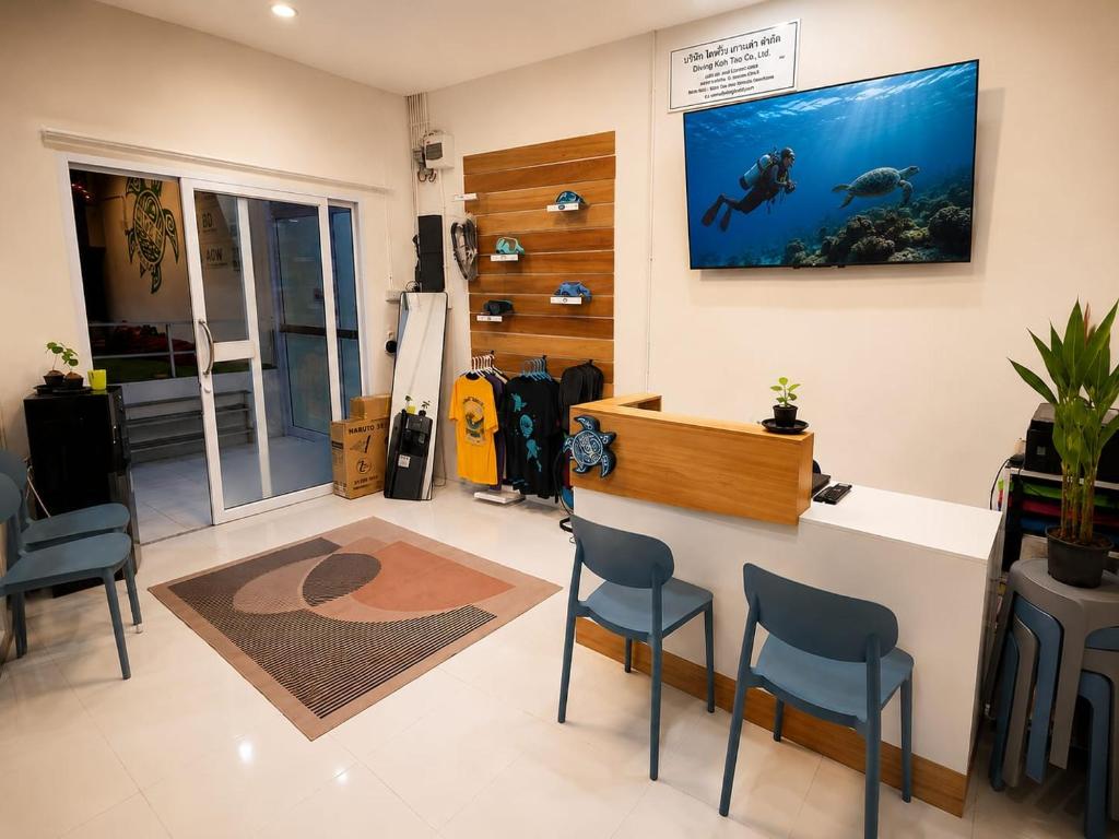 a salon with blue chairs and a fish tank on the wall at Dive In Koh Tao in Ko Tao