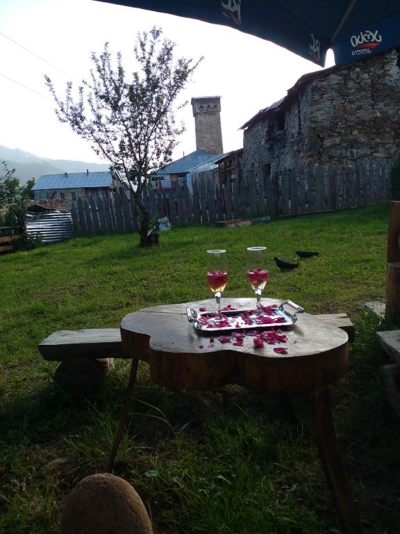 a picnic table with two glasses of wine on it at Iamze's Guest House in Mestia