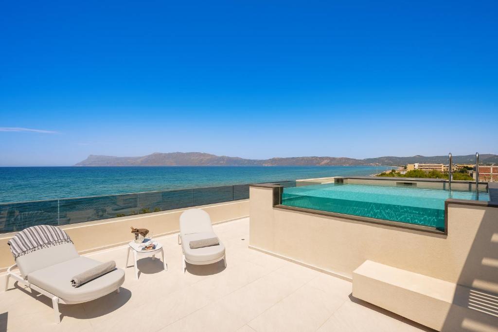 a patio with two chairs and a table and a swimming pool at Sal hotel Kissamos in Kissamos