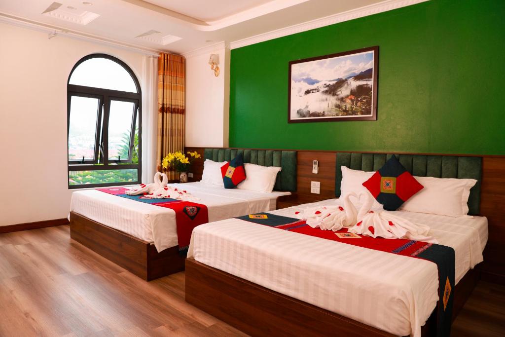 two beds in a room with a green wall at Harmony Haven Hotel in Sapa