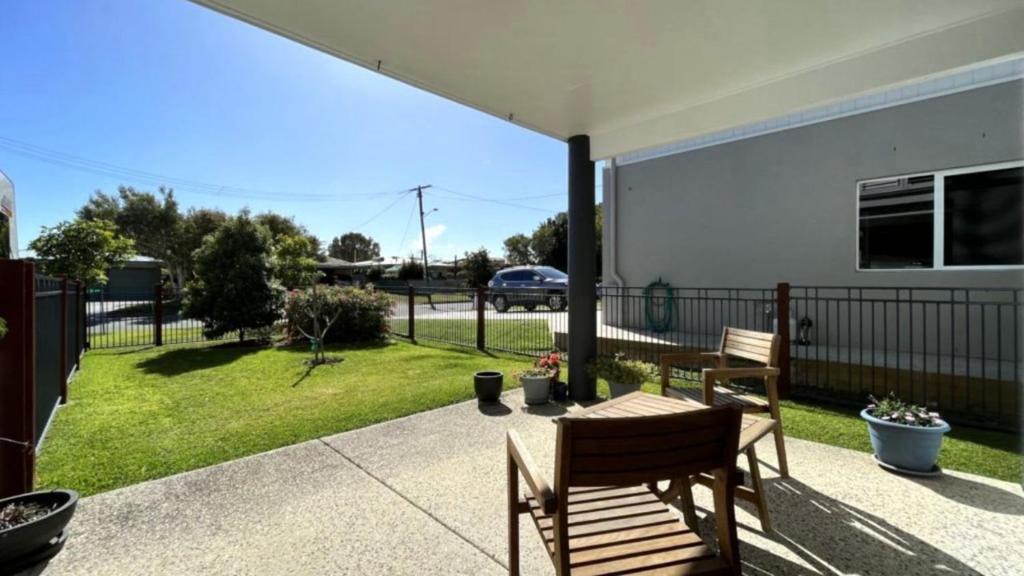 a patio with two wooden benches and a yard at Drakes Hideaway in Golden Beach