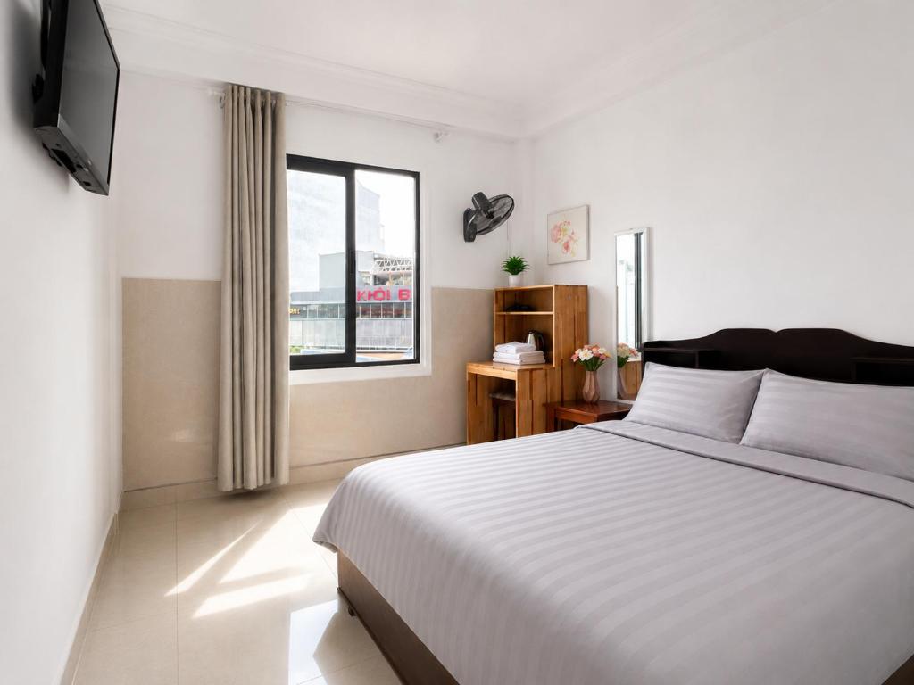 a bedroom with a white bed and a window at Thiên Ngân Hostel in Da Lat