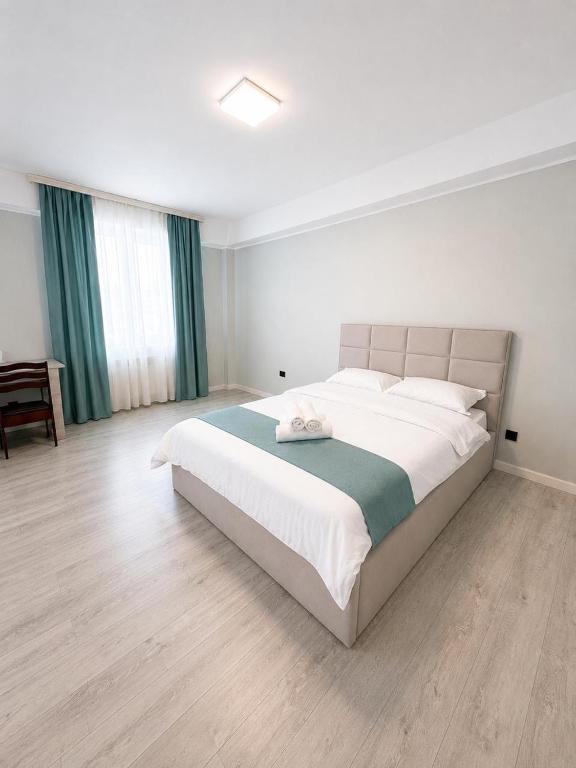 a bedroom with a large white bed with green curtains at Saltanat hotel in Alghabas