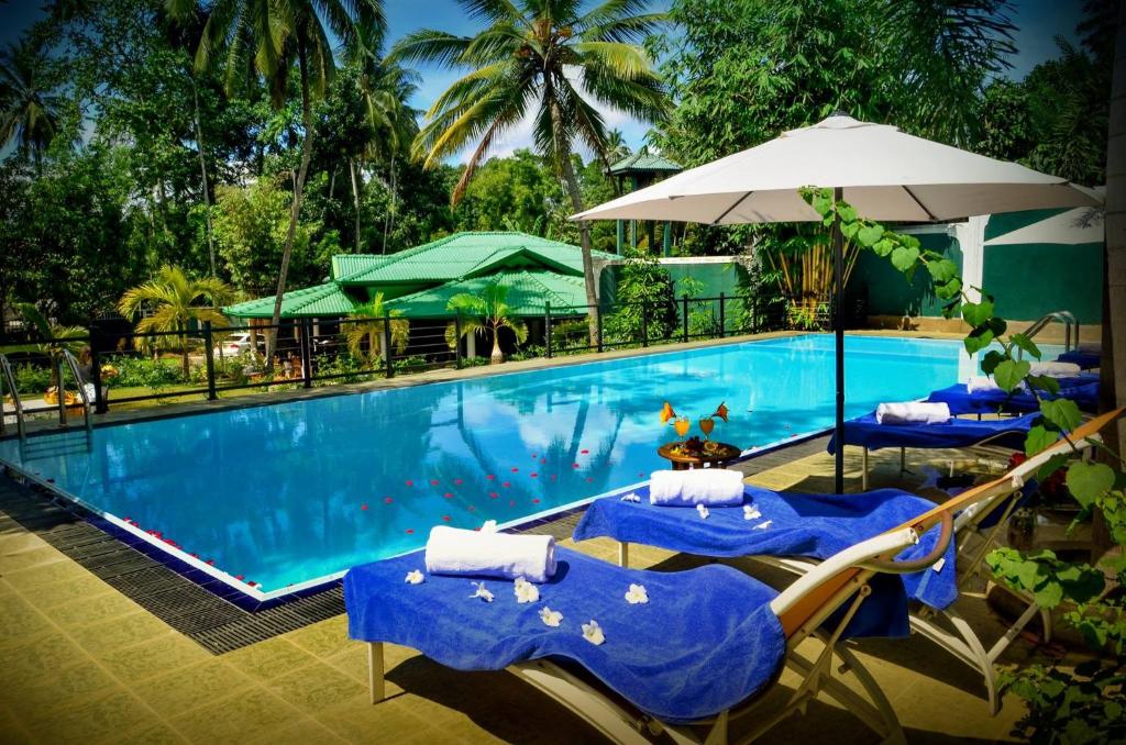 a swimming pool with two lounge chairs and an umbrella at The Kings Villa in Kandy