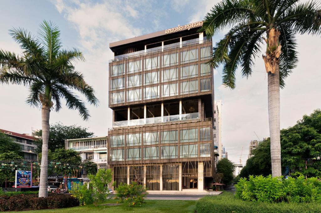 a tall building with palm trees in front of it at SOMA HOTEL Riverside in Phnom Penh