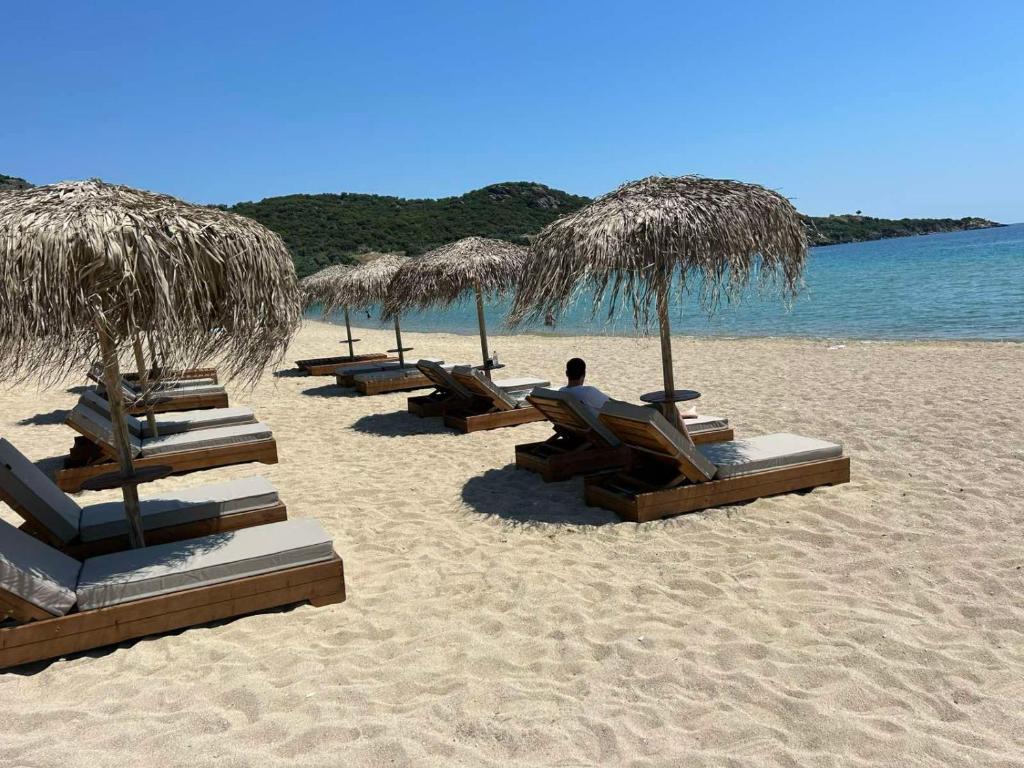 a group of chairs and straw umbrellas on a beach at Sealuxe Living in Iraklitsa