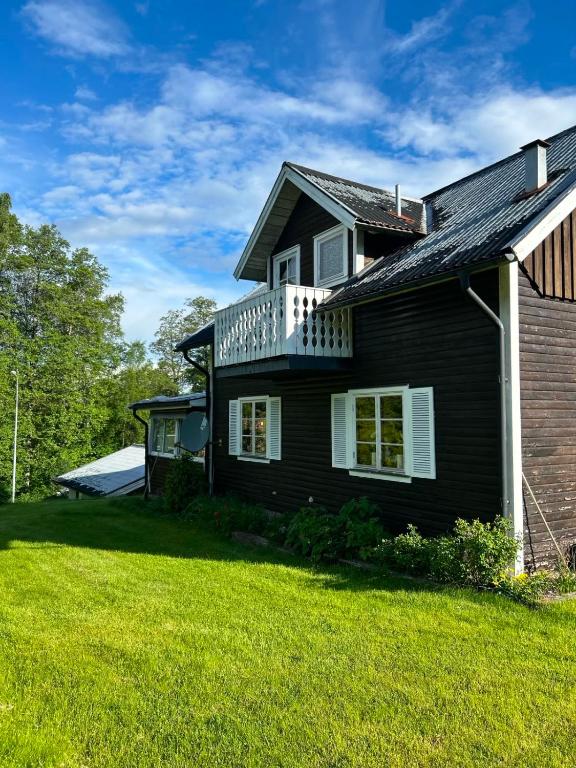 a black house with a balcony on a yard at Schwedentraum in Burseryd