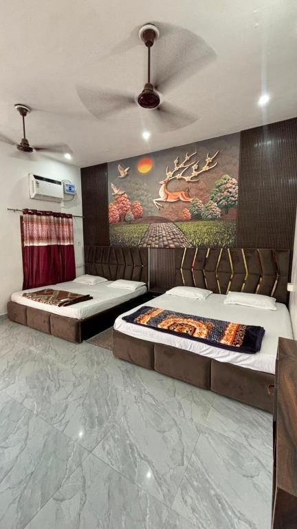 a bedroom with two beds and a painting on the wall at Kanak Bihari Enclave in Ayodhya