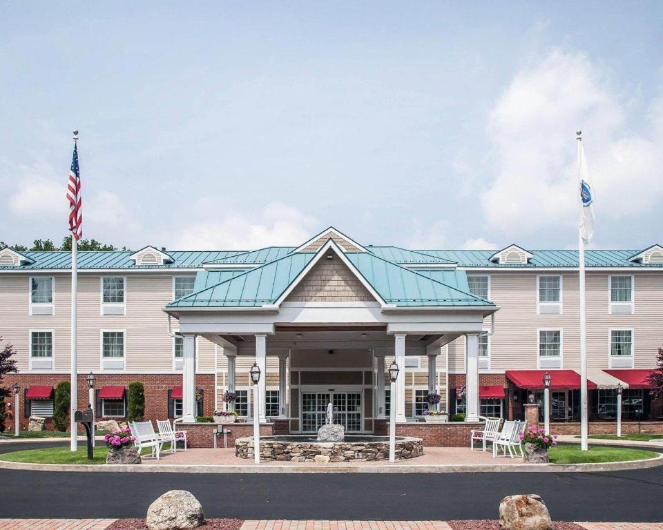 a hotel with two flags in front of a building at Comfort Inn & Suites Sturbridge-Brimfield in Sturbridge
