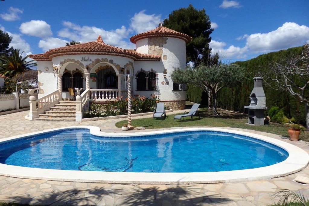 a villa with a swimming pool in front of a house at Meddays Villa Norli in Miami Platja