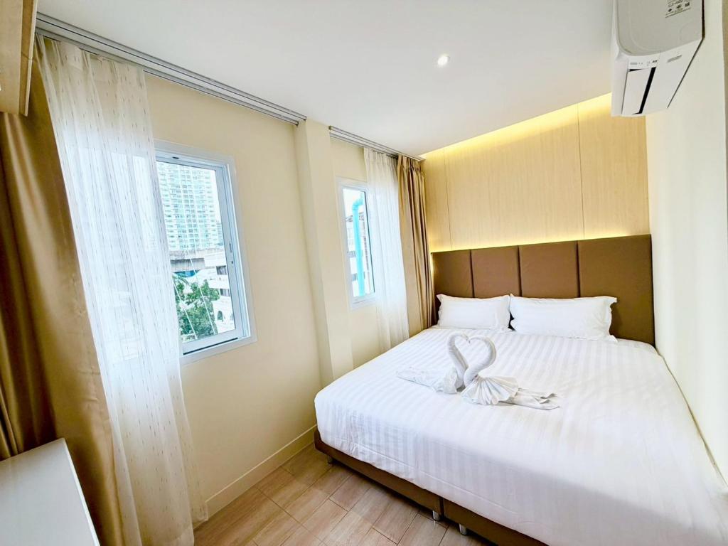 a bedroom with a large white bed with a window at Le Hong Hotel Pratunam in Bangkok