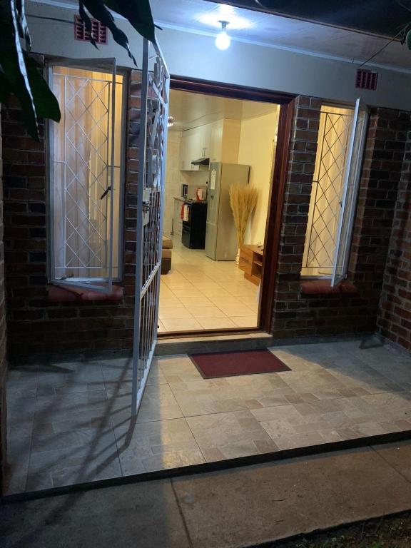 a glass door of a brick house with a hallway at ShanazNest in Bulawayo