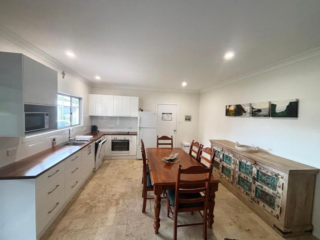 a kitchen with a wooden table and chairs in it at Three Fifty Four Straight St Hat Head - Bring your own linen. in Hat Head