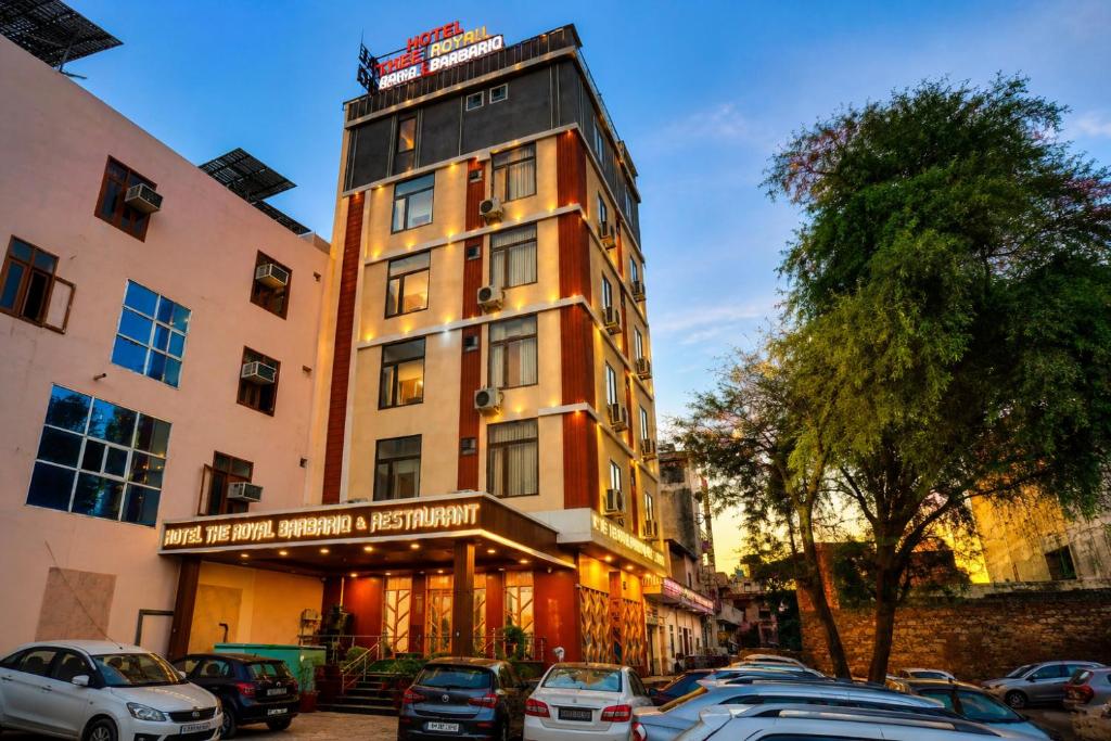 a tall building with cars parked in front of it at Hotel The Royal Barbariq in Khātu