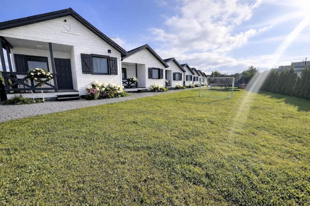 a group of houses with a soccer field in the yard at Czerwone Korale in Sarbinowo