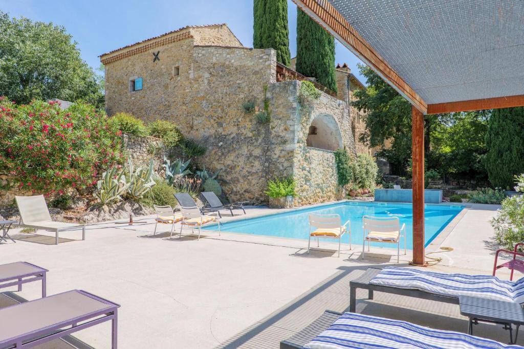 a pool with chairs and a building in the background at Le Mas D'alzon in Vagnas