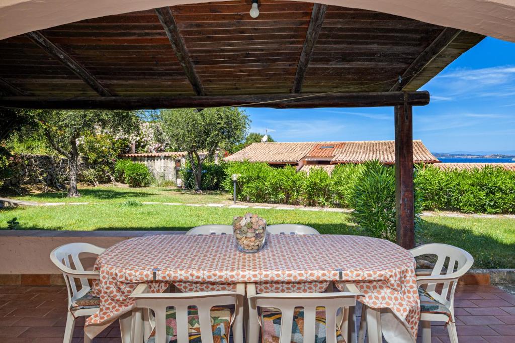 a table with white chairs and a vase on it at Brezza Smeralda- Costa Smeralda in Cala Bitta