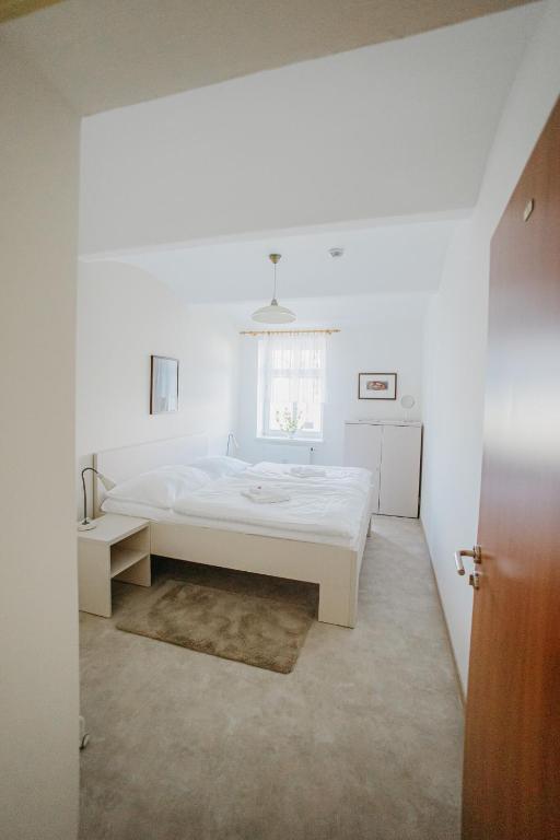 a white bedroom with a large bed and a window at Penzion Albertovec in Opava