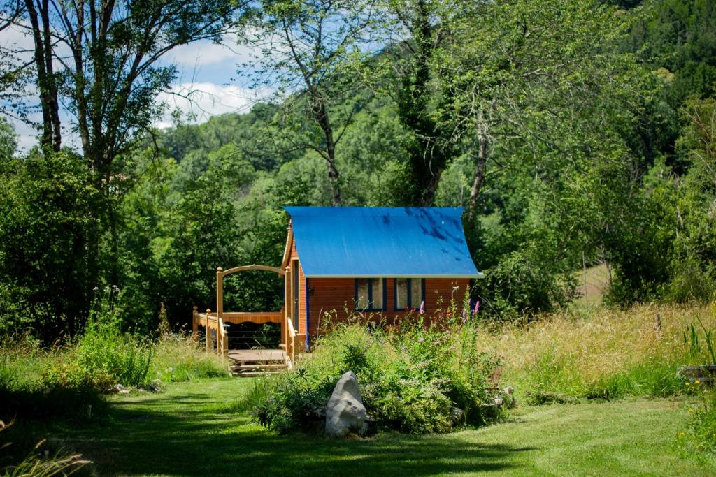 a small red cabin with a blue roof in a field at Tinyhouse insolite - Au bout du chemin - 10 min de Foix in Baulou