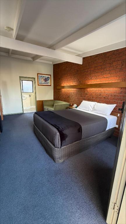 a bedroom with a large bed and a brick wall at Abbotswood Motor Inn in Geelong