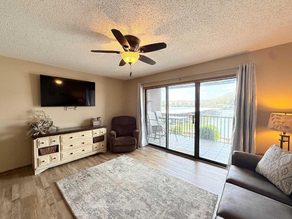 a living room with a ceiling fan and a television at LOTO fun at 21 Lakeview Condo in Osage Beach