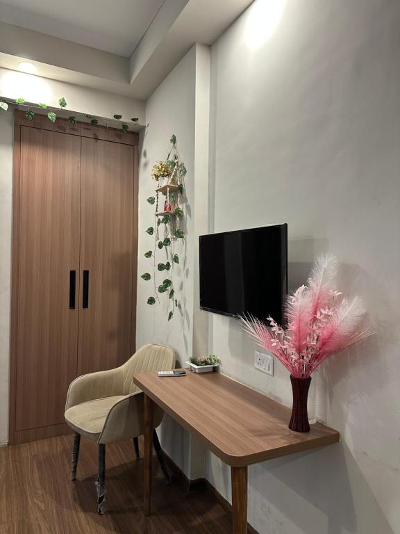 a room with a wooden table and a tv on a wall at Comfort Corner in Greater Noida