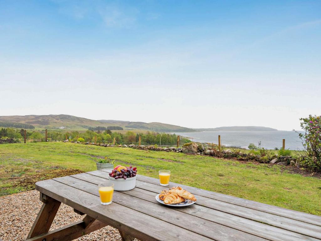 a picnic table with a plate of food and two glasses of orange juice at High Dougarie Farmhouse in Dougarie