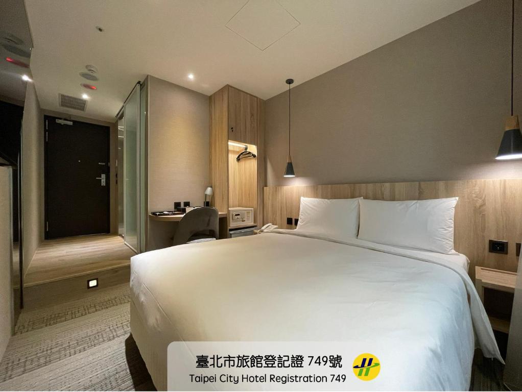 a hotel room with a large white bed and a desk at N Hotel in Taipei