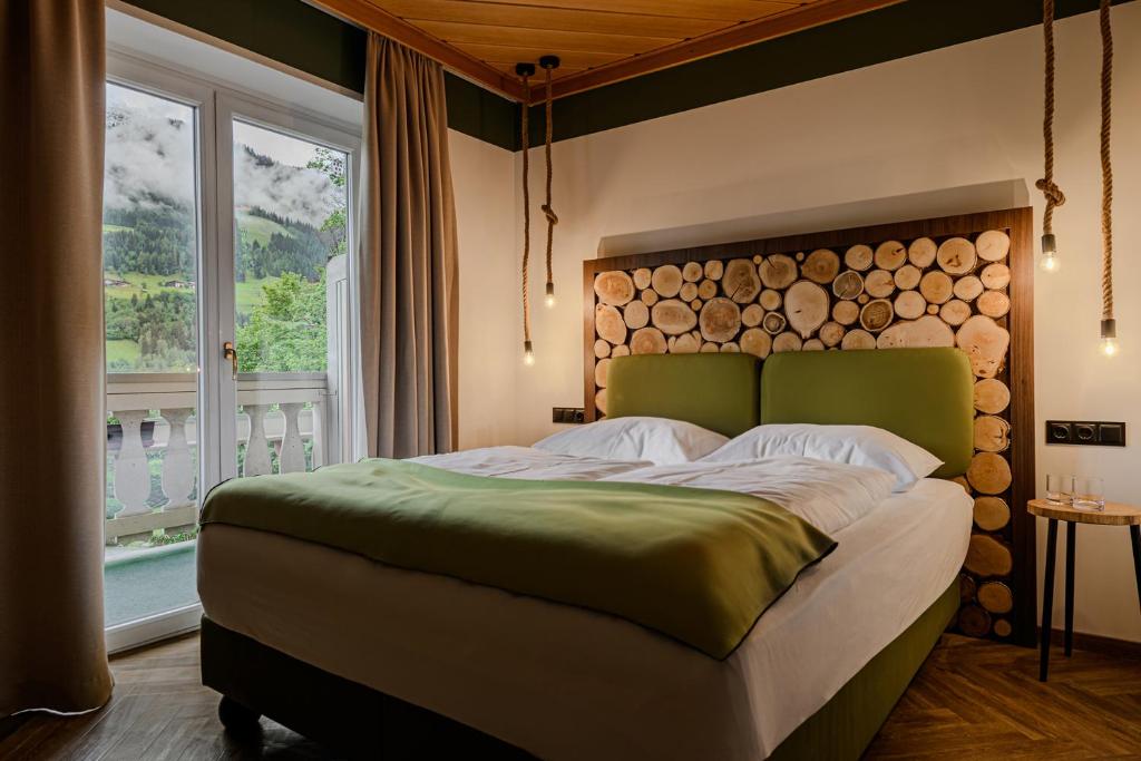a bedroom with a large bed with a wooden headboard at Hotel Völserhof - Bergbahn im Sommer 2026 inklusive in Bad Hofgastein