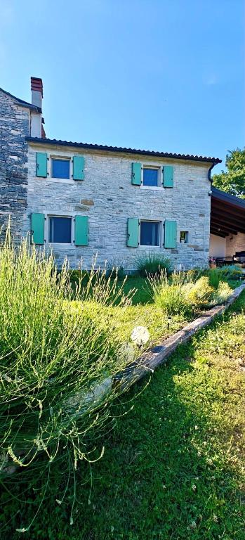 a building with green shuttered windows in a field at Casa Evelina in Čepić