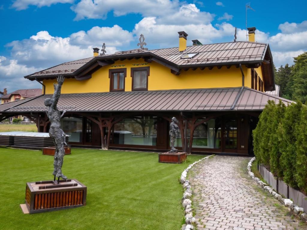 a house with a tree in the front yard at Asiago Sporting Lodge - Buongiorno! Hotels in Asiago