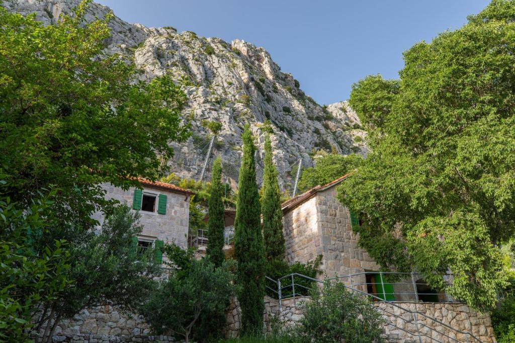 a stone house in front of a mountain at Holiday Homes Baučić in Omiš