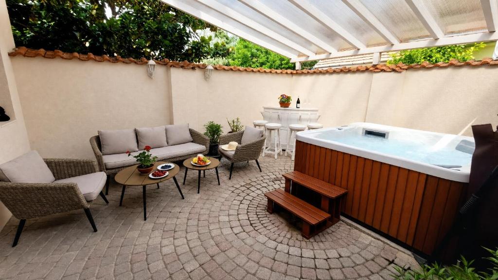 a patio with a hot tub and chairs and a table at Chillinn La Maison Cottage Eger in Eger