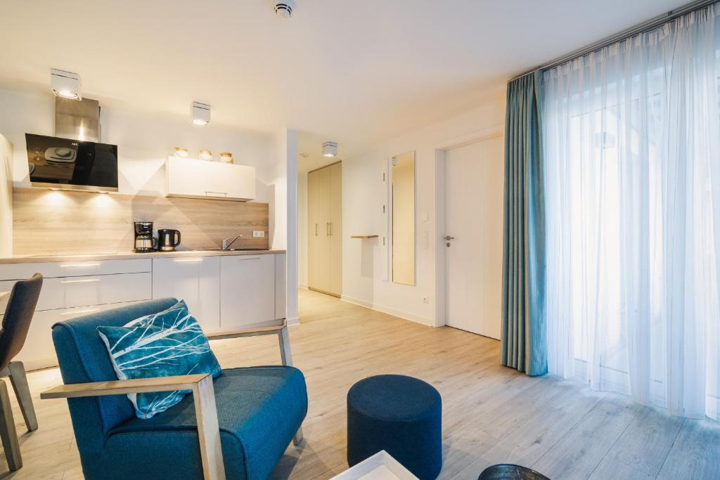 a living room with a blue chair and a kitchen at Am Park 3 in Prerow