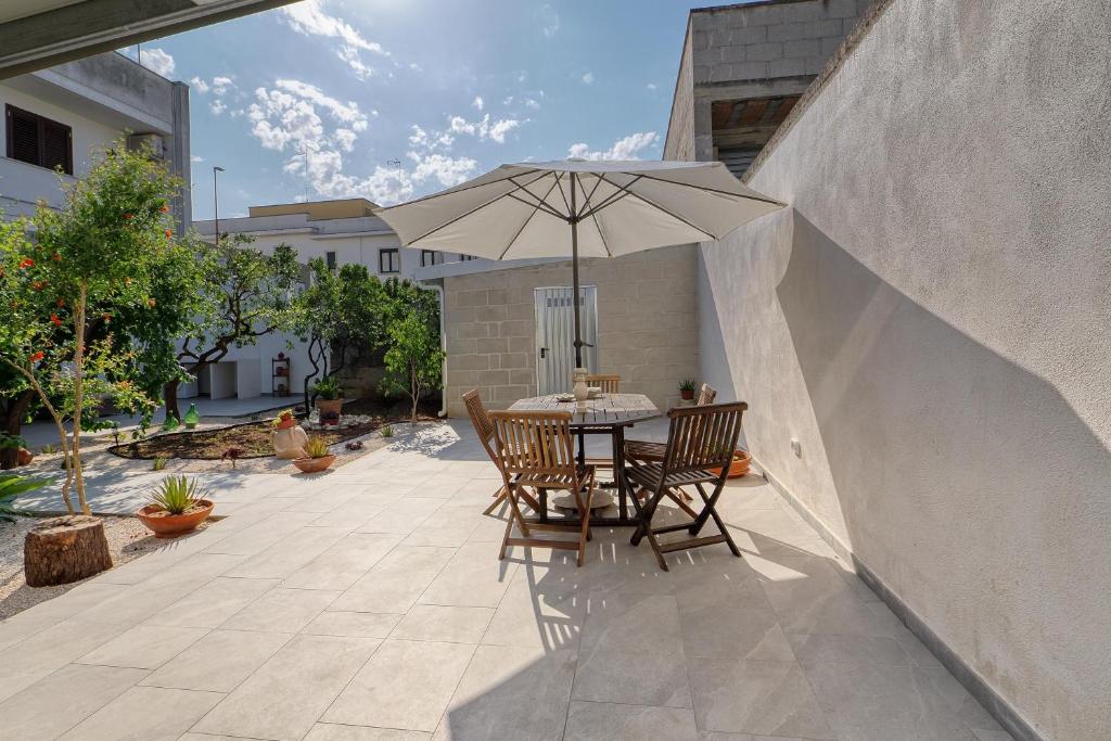 a table and chairs with an umbrella on a patio at Agrù - Salento Garden Stay in Cavallino di Lecce